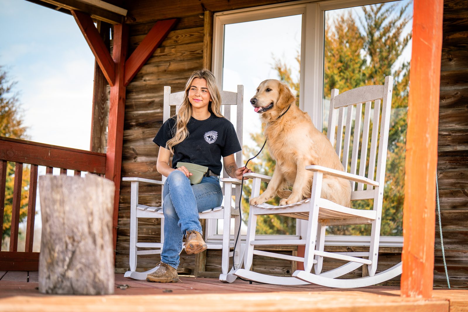 Trainer with a golden retriever on a sunny porch